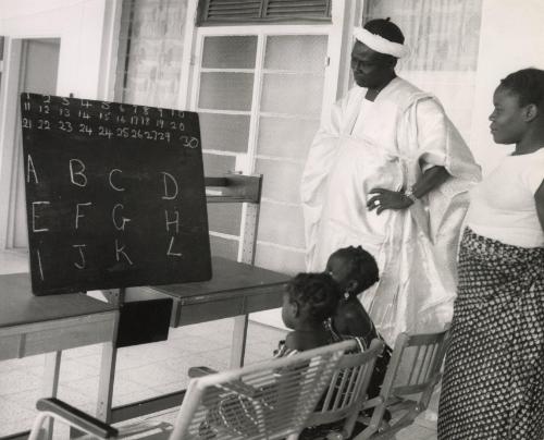 Family at home teaching their children the alphabet, likely Dakar, Senegal, Africa, 1959
